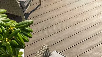 High-angle view of a patio with light brown, ribbed decking, wicker furniture, and corner plants.