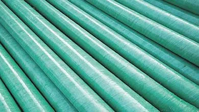 Close-up, diagonal view of several large green pipes wrapped in textured material.