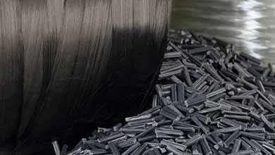 Close-up of dark carbon fibers bundled together beside a pile of chopped carbon fiber pellets.