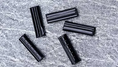 Five black, ridged rectangular objects scattered on a gray brushed metal surface.