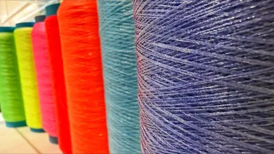 Large spools of brightly colored yarn arranged side by side in a textile facility.