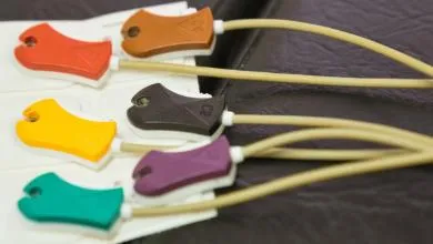 Close-up of six colorful ECG electrode clips—red, yellow, green, brown, black, and purple—attached to tan wires.